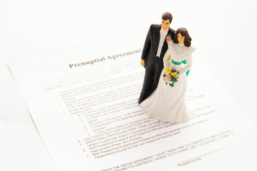 Figurines of a bride and groom on top of a prenuptial contract