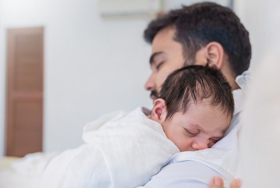 A man sleeps with a sleeping baby on his chest