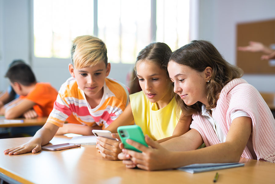 young children looking at their mobile phones in a classroom