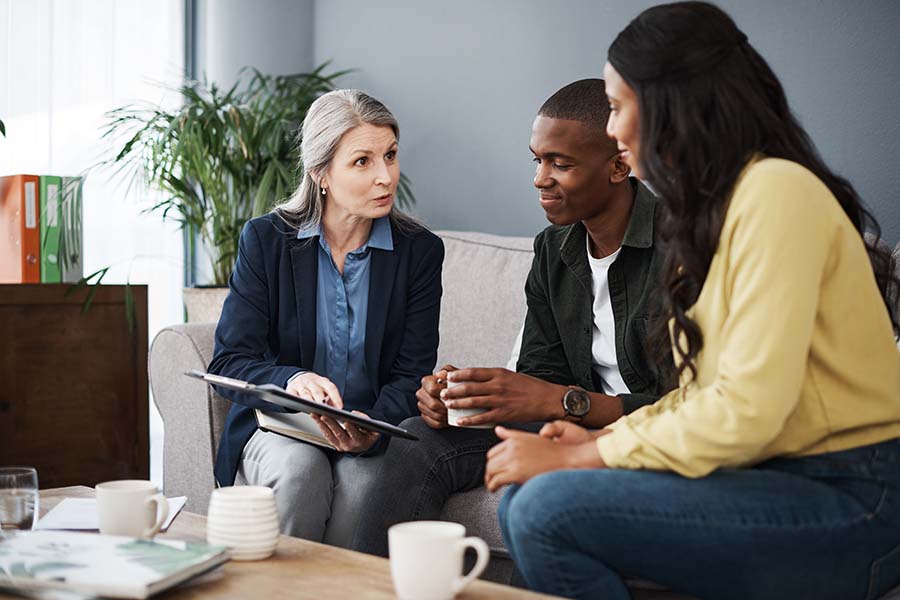 A young couple examine a form being shown to them by a solicitor