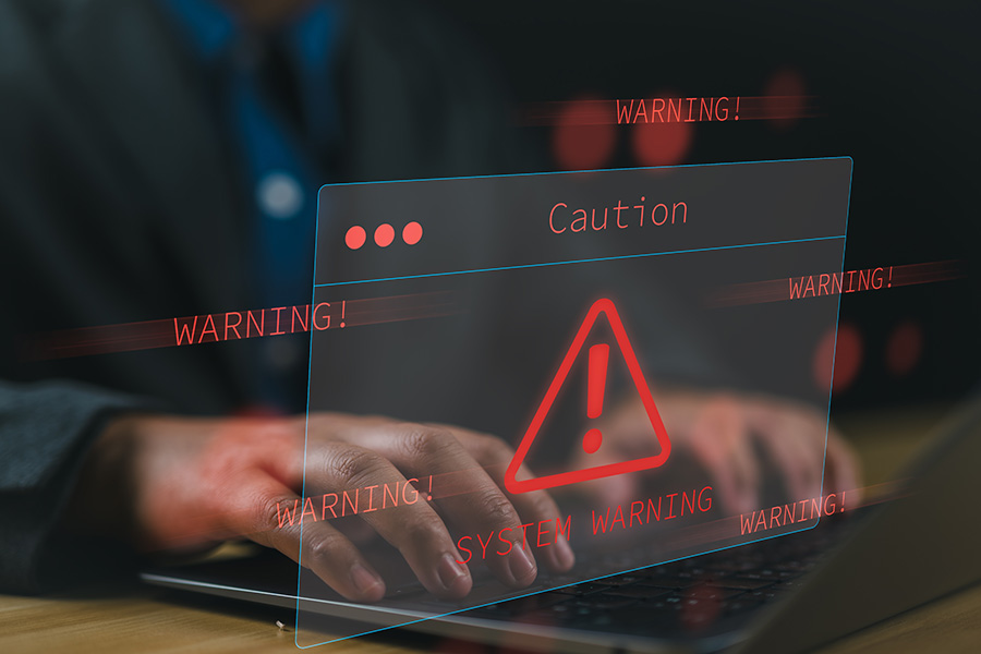 Hands on a laptop overlaid with a graphic of red warning signs