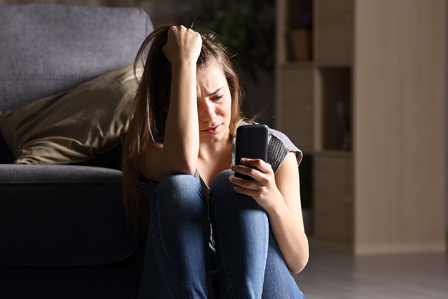 A young woman looks distressed while looking at her phone