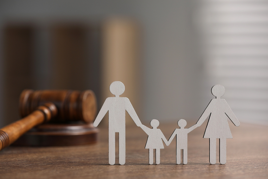 Family law. Figure of parents with children and gavel on wooden table, space for text