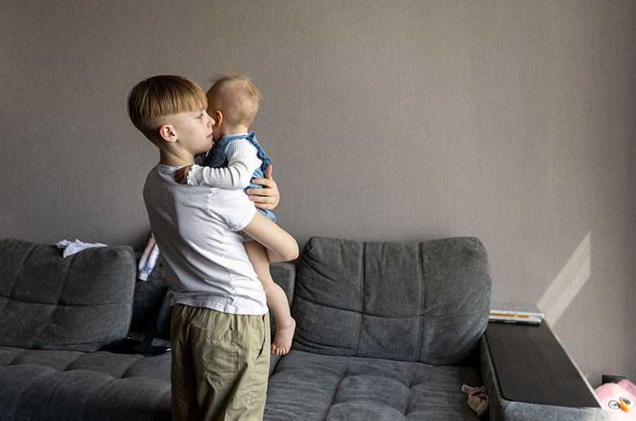 A young boy hugging his baby sister