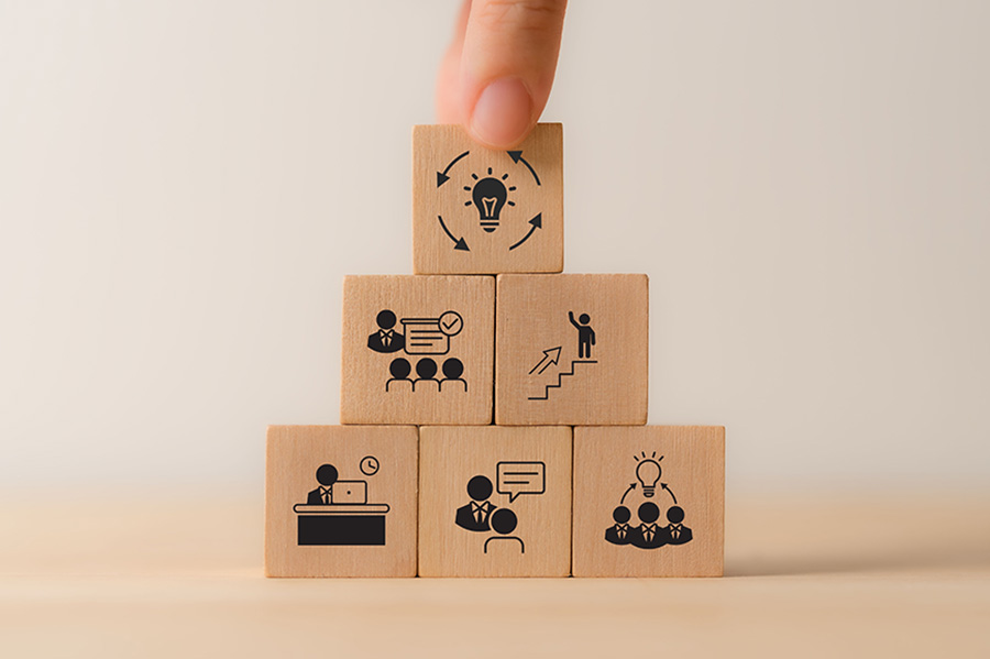 A stack of wooden bricks with simple illustrations of workplace concepts