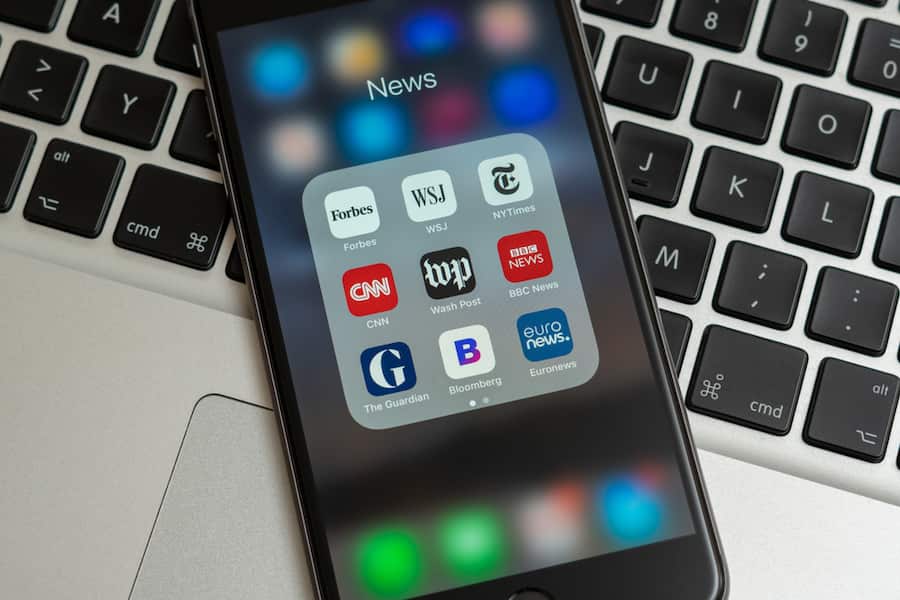 A mobile phone showing apps of several major news publications