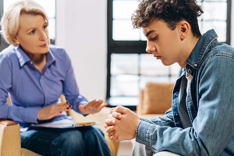 An unhappy looking teenage boy with a professional older woman