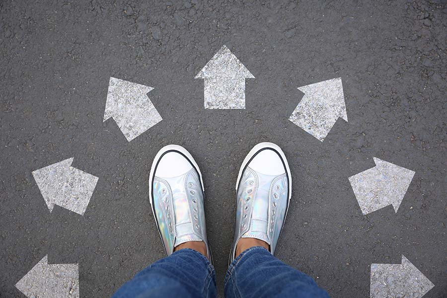 A woman's feet in silver trainers surrounded by arrows pointing in different directions