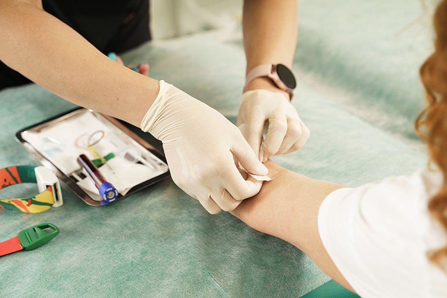 A close up of a nurse preparing to take a sample of blood from a young woman's arm
