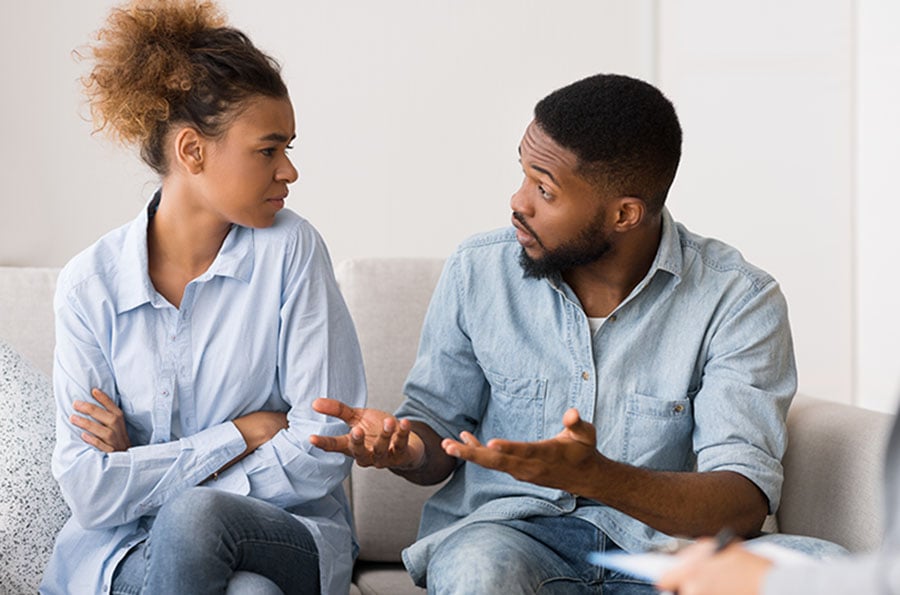 A couple in discussion while a therapist/solicitor looks on