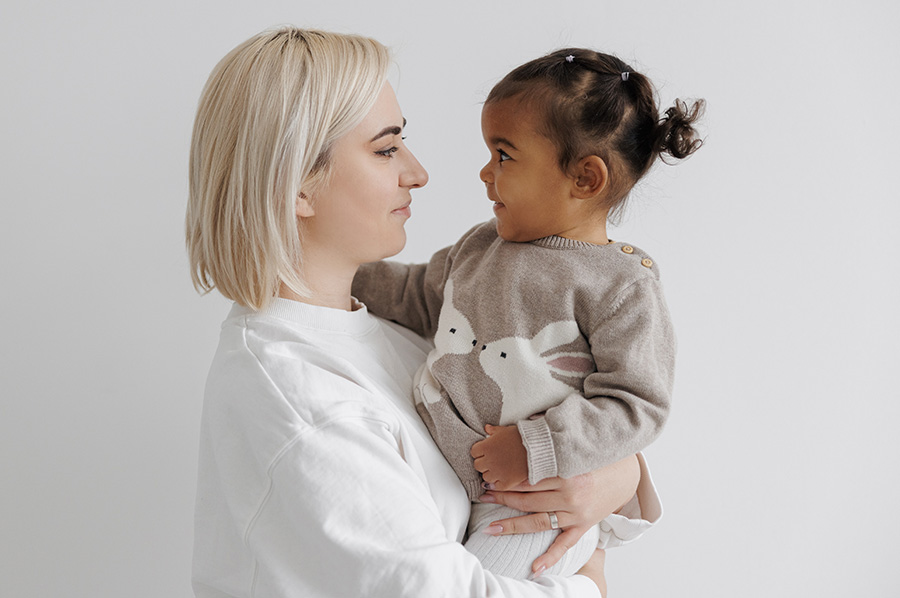 A young white woman holding a black toddler
