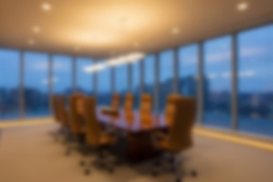 A luxurious, modern executive boardroom with a panoramic city view at dusk.