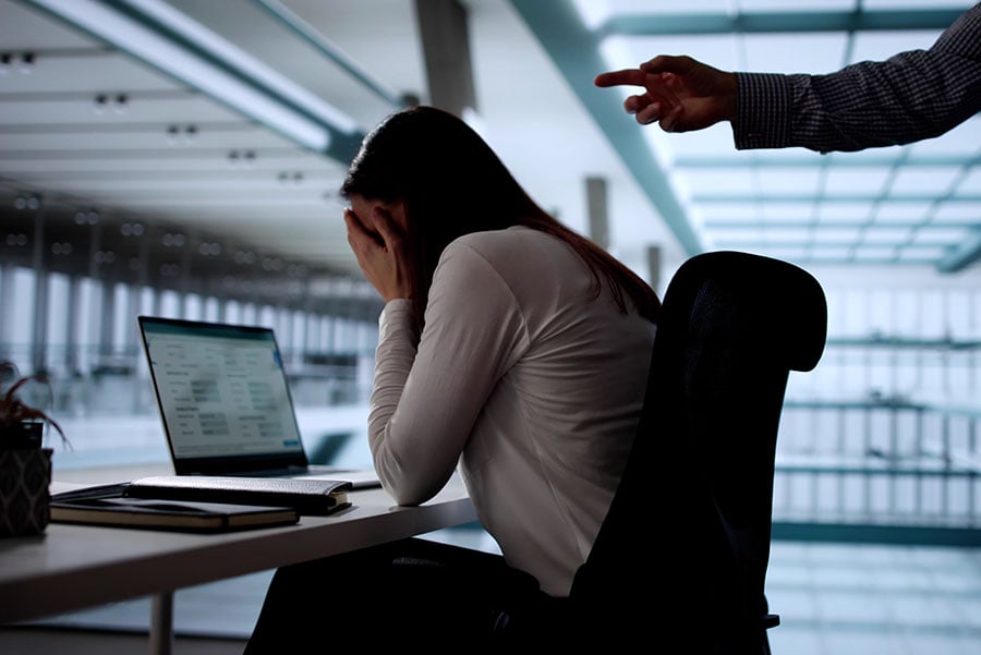 A bullied employee at work being pointed at by an angry boss