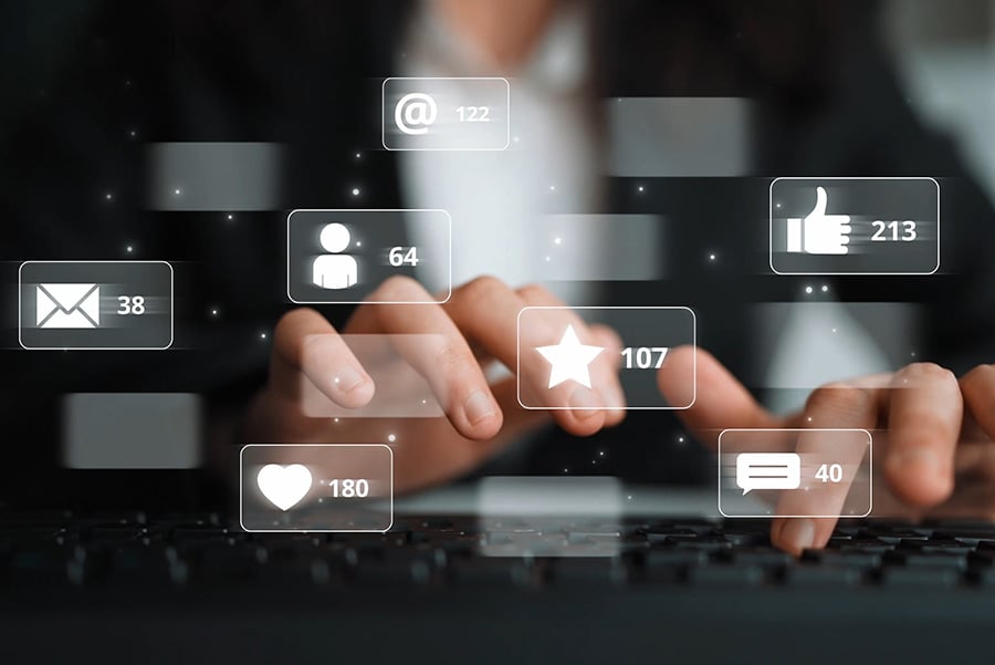 A woman in a black suit and white shirt typing on a keyboard, overlaid with graphics of symbols including emails and social media icons