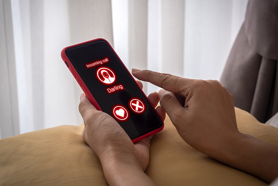 A mobile phone displaying an incoming call in red with a heart logo
