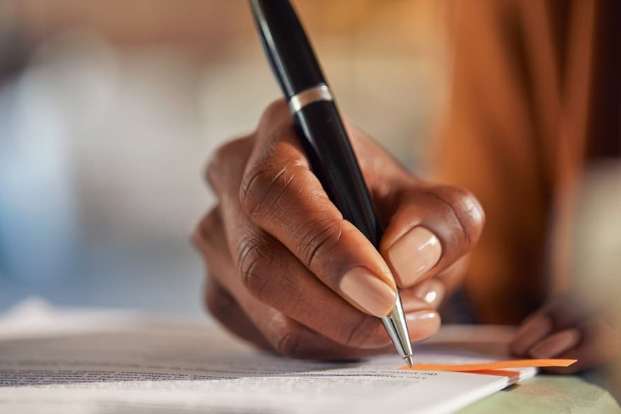 Close up of a hand writing on a nuptial agreement