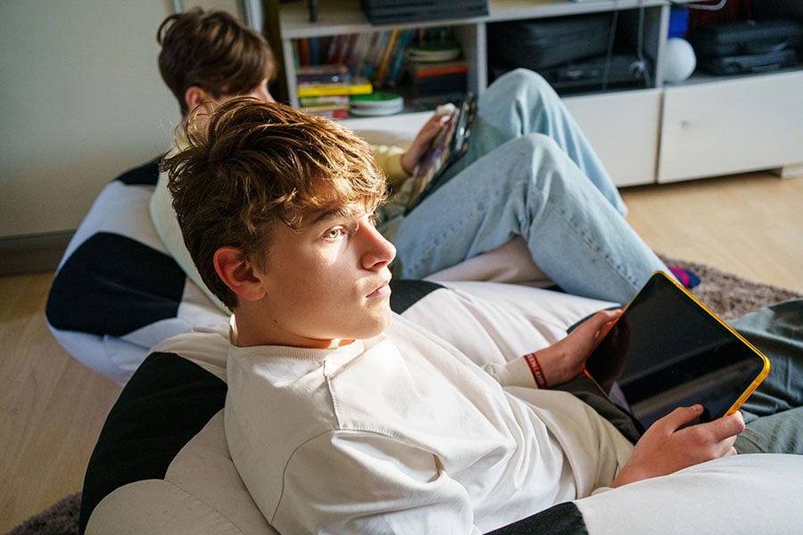 Teenage boys sitting on beanbags and using tablets