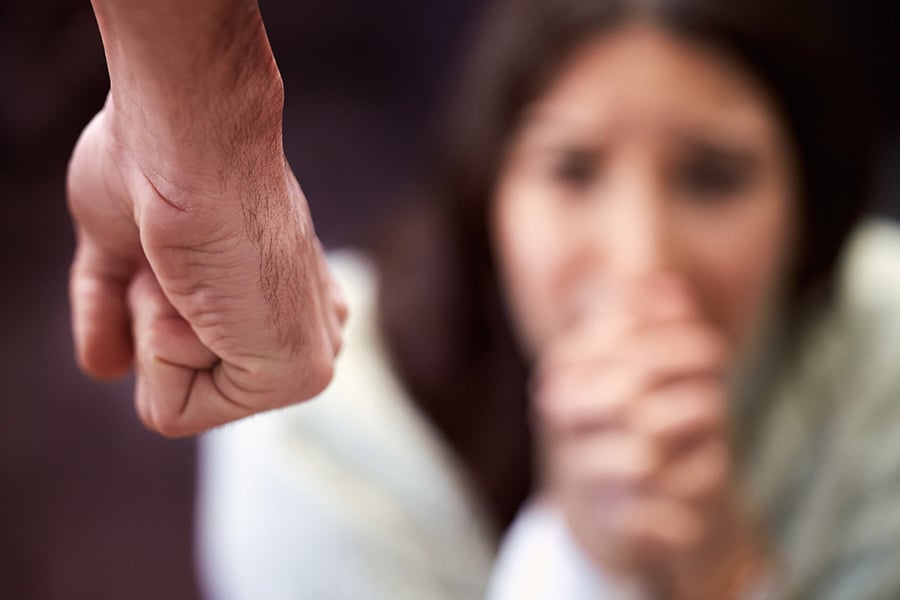 A close-up of a clenched fist, with a scared looking woman in the background