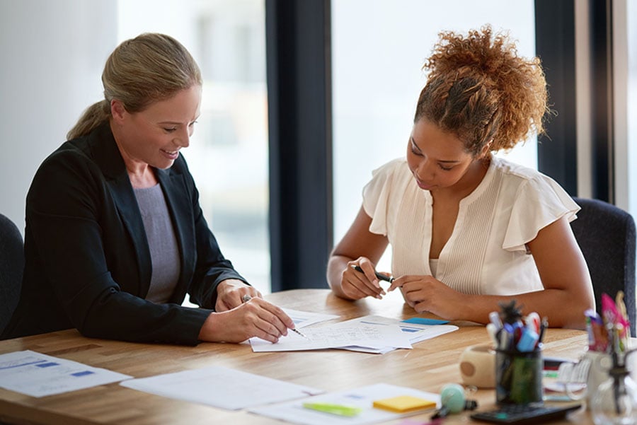 A lawyer and client discuss paperwork at a desk
