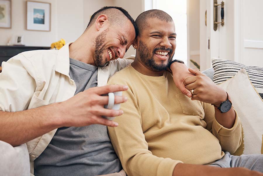 A married male couple smiling happily on the sofa