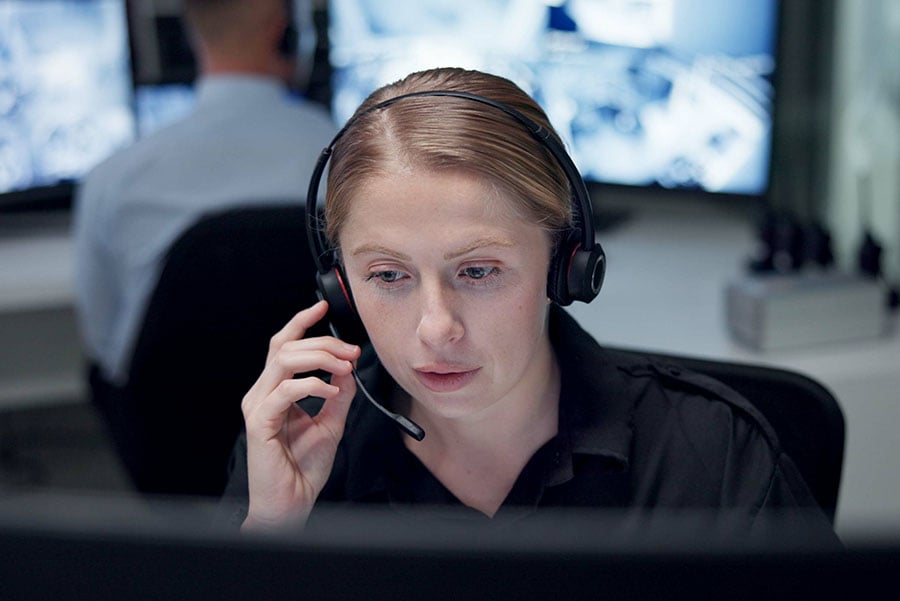 A woman using a headset in a police control room