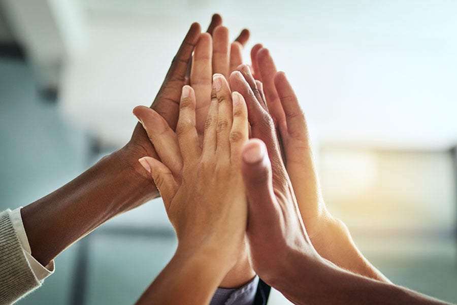 People with different skin colours hold hands up together